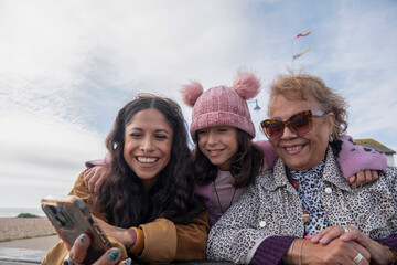 Poster - Grandmother, mother and daughter looking at smart phone on beach