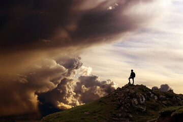 Wall Mural - Ein Mann steht auf einem Berg und schaut in eine fantastische Wolkenlandschaft