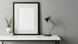 © standret - mock up of a small blank black frame, horizontal orientation, on a white table and black lamp, gray wall