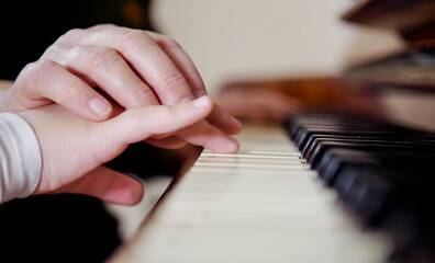 Experienced hand of the old music teacher helps the child student. Experienced master piano hand helps the student, close-up.