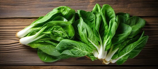 Wall Mural - A collection of fresh and vibrant bok choy leaves neatly arranged on top of a solid wooden table surface, creating a simple yet visually appealing display of healthy greens.