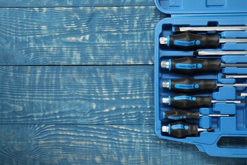 Sticker - Set of screwdrivers in open toolbox on blue wooden table, top view. Space for text