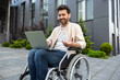© zinkevych - Bearded man in wheelchair working on laptop and looking contented