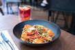 Close-up of spaghetti with shrimp served with a glass of fruit drink in the restaurant.