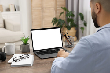 Poster - E-learning. Young man using laptop at wooden table indoors, closeup