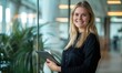 © LoLArt - Young beautiful blond caucasian business woman or CEO executive manageer standing in light office with glass walls holding tablet and smiling at camera