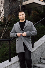 Wall Mural - A handsome man in a gray coat is walking on the street.