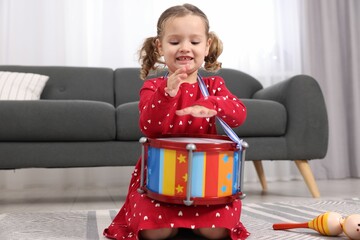 Wall Mural - Little girl playing toy drum at home