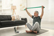 © New Africa - Senior man doing exercise with fitness elastic band near laptop on mat at home