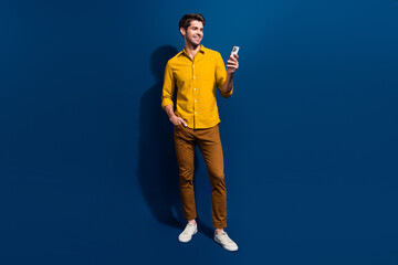 Poster - Full size photo of attractive young man hold device read post news dressed stylish yellow clothes isolated on dark blue color background