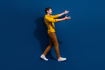 Sticker - Full length photo of nice young male walk stretching hands want hug wear trendy yellow garment isolated on dark blue color background