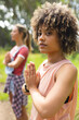 © Wavebreak Media - Young biracial woman with curly hair practices yoga outdoors, hands pressed together