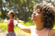© Wavebreak Media - Young biracial woman with curly hair enjoys a moment of relaxation outdoors, eyes closed and arms ou
