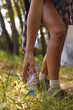 © Wavebreak Media - Person picks up a plastic bottle from the grass in a wooded area, collecting trash