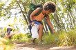 © Wavebreak Media - Young biracial woman picks up trash while hiking, promoting environmental care