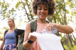 © Wavebreak Media - Young biracial woman with curly hair is putting a water bottle into a bag, outdoors, collecting tras