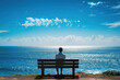 A man sitting on a bench, looking out at the ocean on a sunny day