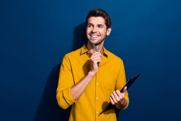 Canvas Print - Photo portrait of attractive young man paperholder look empty space dressed stylish yellow clothes isolated on dark blue color background