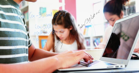 Canvas Print - Image of mathematical equations floating over schoolchild using laptop computer with classmates in t