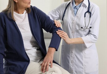 Sticker - Arthritis symptoms. Doctor examining patient's elbow in hospital