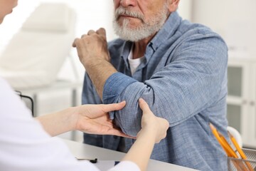 Wall Mural - Arthritis symptoms. Doctor examining patient's elbow in hospital, closeup