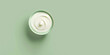 Creamy cream in a cup on a green background, top view