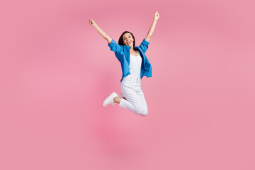 Full length photo of overjoyed woman wear blue jacket white pants jumping raising fists up win bet isolated on pink color background