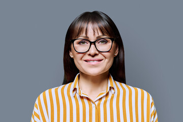 Wall Mural - Portrait of smiling middle aged woman with on grey background