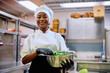 © Drazen - Happy black female cook working in restaurant and looking at camera.