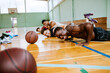 © Marko Geber - Exhausted basketball player resting on the court with teammates