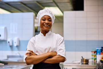 Wall Mural - Confident black female chef in kitchen looking at camera.