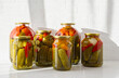 Pickled cucumbers and tomatoes in glass jars. Isolated on a white background. Close up.