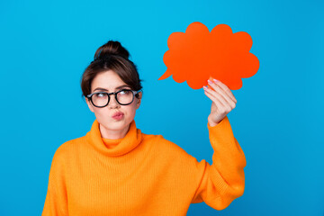 Canvas Print - Photo of suspicious unsure woman dressed orange sweater eyewear holding looking speaking bubble empty space isolated blue color background