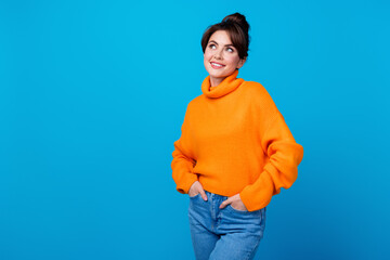 Photo of positive dreamy woman dressed orange sweater looking empty space isolated blue color background