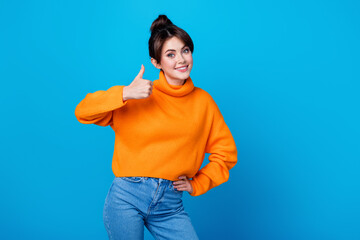 Sticker - Photo of cheerful confident woman dressed orange sweater showing thumb up empty space isolated blue color background