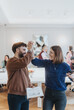 © qunica.com - Joyful professional interaction captured as two colleagues high-five in a well-lit office setting, symbolizing team success, support, and positive workplace culture, with other people in the