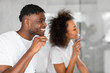 © Prostock-studio - black spouses doing dental care routine brushing teeth near mirror