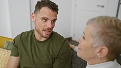 Wall Mural - A woman and man engage in conversation, sitting together in a cozy indoor living room setting.