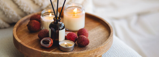 Oriental interior, Bali, Thai vibes banner. Sweet home perfume with tropical exotic fruits. Reed diffuser on wooden tray in a bedroom. Burning candles, atmosphere of relaxation, detention, meditation