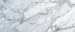 Detailed close-up of a white Carrara marble texture, showcasing the intricate veins and speckles characteristic of this stone. The surface appears smooth and polished,