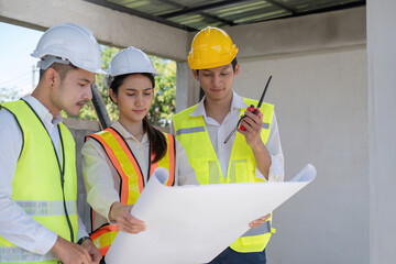 Wall Mural - Civil engineer teams meeting working together wear worker helmets hardhat on construction site in modern city. Foreman industry project manager engineer teamwork. Asian industry professional team