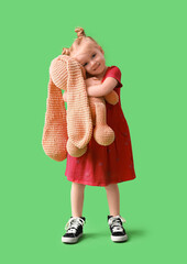 Wall Mural - Cute little girl hugging toy bunny on green background