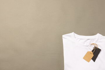 Wall Mural - A plain white t-shirt with a price tag attached lies against a neutral background, with copy space