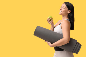 Sticker - Beautiful young happy woman with yoga mat and fresh apple on yellow background. Weight loss concept