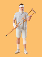 Sticker - Injured young man after accident with crutch on yellow background