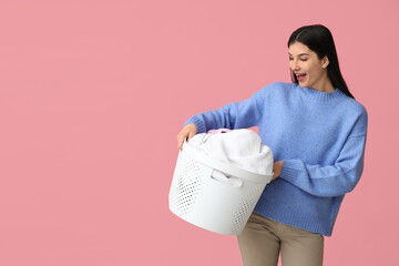 Sticker - Beautiful young woman holding basket with clean laundry on pink background