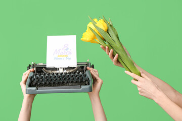 Wall Mural - Female hands with retro typewriter, greeting card and beautiful tulip flowers on green background, closeup. International Women's Day