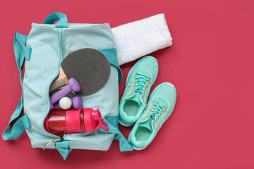 Wall Mural - Sports bag with sportswear, water and ping pong equipment on red background