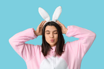 Beautiful young woman in bunny costume on blue background. Easter celebration