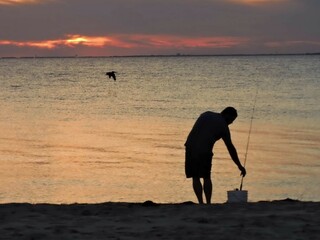 Wall Mural - silhouette of a person fishing on at sunset